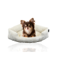 Ein gemütliches, beiges Haustierbett mit gerippter Textur, in dem ein kleiner Hund bequem sitzt.