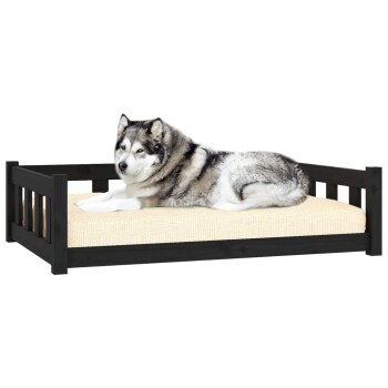 Ein flauschiger grau-weißer Hund liegt bequem auf einem schwarzen Holzhaustierbett mit einem beigen Kissen.