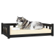 Ein flauschiger grau-weißer Hund liegt bequem auf einem schwarzen Holzhaustierbett mit einem beigen Kissen.