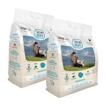 Deux sacs de nourriture pour chiens Swiss Natural Senior Mini, chacun de 1 kg, avec un arrière-plan pittoresque d'une personne et d'un chien.