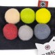 Sechs bunte Filzkugeln in beige, grün, gelb, rot, grau und hellgrau auf einem schwarzen Hintergrund mit einem Katzen-Silhouette-Tag.