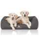 Zwei Golden Retriever Welpen, die bequem in einem grauen Hundebett sitzen, mit dem Logo 'KNUFFELWUFF' deutlich sichtbar.