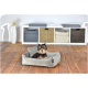 Ein kleiner Yorkshire Terrier sitzt bequem in einem grauen Hundebett auf einem Holzboden, mit einem modernen Aufbewahrungseinheit im Hintergrund.