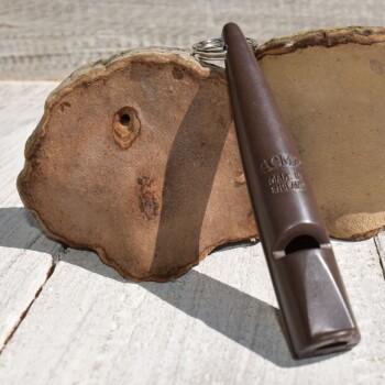 Hand hält eine 80 mm schwarze Pfeife mit Schlüsselring, Lanyard-Clip und zweisprachiger Bedienungsanleitung von ACME Special Whistles.