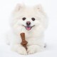 A fluffy white dog rests its paws on a wooden chew toy against a plain white background.