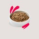 A white bowl filled with brown pet kibble, set against a light background with pink brushstroke accents.