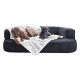 Zwei Hunde, ein großer brauner und ein kleiner schwarzer, ruhen auf einem dunkelgrauen Sofa, das mit einer weißen Decke bedeckt ist.