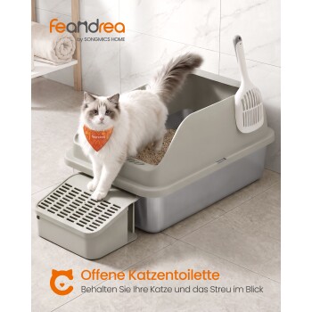 Weiße langhaarige Katze mit orangefarbenem Halstuch auf offener grauer Katzentoilette mit Rampe; sichtbarer Text: 'feandrea', 'Offene Katzentoilette'.