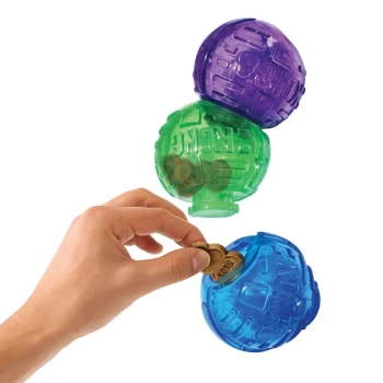 Lock-It Snack Toy A hand is placing a dog treat into a blue KONG toy, with a green and purple KONG toy stacked above it.