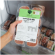 Hand hält eine gefrorene 400‑g‑Schale mit der Aufschrift ‚Komplett‑Mix Geflügel für Katzen‘, Fleischplättchen im Gefrierfach.