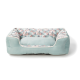 Un lit pour animaux doux et rectangulaire avec un extérieur bleu clair et un motif géométrique coloré en rose, gris et blanc à l'intérieur.