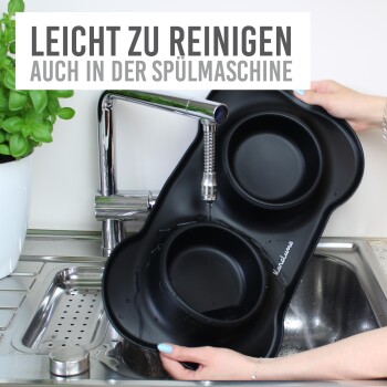 Eine Person hält eine schwarze Fressnapf unter einen Wasserhahn, aus dem Wasser fließt. Der Text darüber sagt "EINFACH ZU REINIGEN, AUCH IM GESCHIRRSPÜLER."