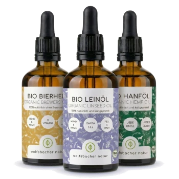 Drei Flaschen mit Haustierergänzungen: Bio-Hanföl, Bio-Leinsamenöl und Bierhefe, jede mit Zutaten und Vorteilen beschriftet.