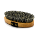 Eine Holz-Haustierpflegebürste mit dichten schwarzen und beigen Borsten, mit einem schwarzen Riemen mit zwei goldenen Knöpfen.