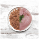 Ein weißer Teller, der in zwei Hälften geteilt ist, mit zerbröckeltem braunem Haustierfutter auf der linken Seite und rohem pinkem Fleisch mit grünem Garnitur auf der rechten Seite.