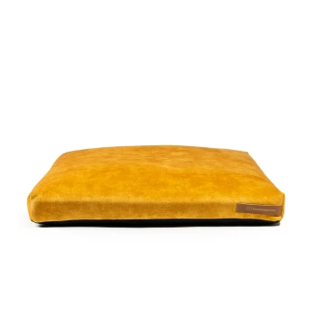 Gelbes Haustierbett mit einer weichen, wildlederähnlichen Textur und einer schwarzen Unterseite, mit einem kleinen Etikett mit der Website "theproduct.com."