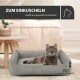 Eine getigerte Katze liegt in einem gemütlichen Bett, umgeben von einem Holztisch und Dekoration. Text: "ZUM EINKUSCHELN" und "schafft ein gemütliches Ambiente."
