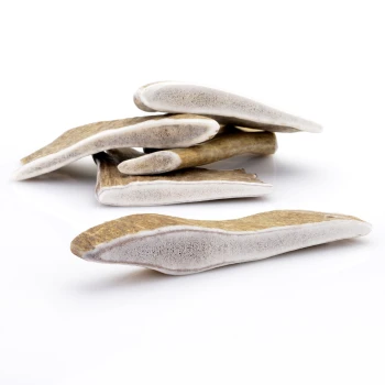 Ein Haufen natürlicher Hundekauartikel, die wie Geweihstücke aussehen, mit einer hellbraunen und weißen Farbe und einer glatten Textur.