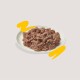 Une assiette de nourriture pour animaux humide, finement hachée, ressemblant à une pâte de viande, posée sur un fond clair avec des accents jaunes ludiques.