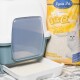 Eine Katzenstreu-Box mit einer transparenten Klappe, neben einem Sack Lyra Pet White Cat Streu, mit einem Bild einer weißen Katze und Text auf Deutsch.