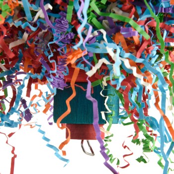 Buntes, zerrissenes Papier in verschiedenen Blau-, Grün-, Orange- und Lilatönen, das von einem Holzspielzeug für Haustiere hängt.