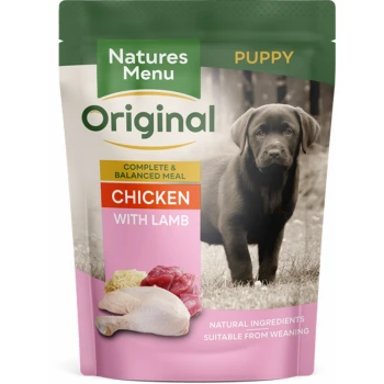 Pouch of Natures Menu Original puppy food featuring chicken with lamb, with a black Labrador puppy in the background.