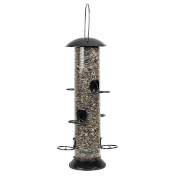 Ein hoher, zylindrischer Vogelfutterspender, gefüllt mit Sonnenblumenkernen, mit vier Futteröffnungen und einer schwarzen Kappe und Basis.