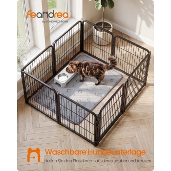 Katze frisst aus einem erhöhten Napf in einem schwarzen Metall-Auslaufgehege auf grauer Matte; Text 'feandrea' und 'Waschbare Hundeunterlage'.