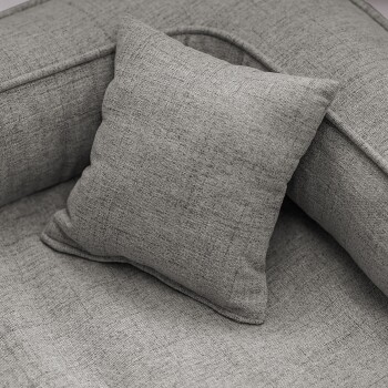 Graues Haustierbett mit gepolstertem Boden und erhöhten Seiten, mit einem kleinen Kissen, auf einem hellen Holzboden platziert.