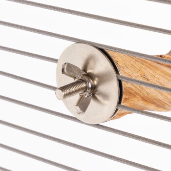 Nahaufnahme einer Metallschraube und einer Holzsitzstange für einen Haustierkäfig, mit horizontalen Metallstäben im Hintergrund.