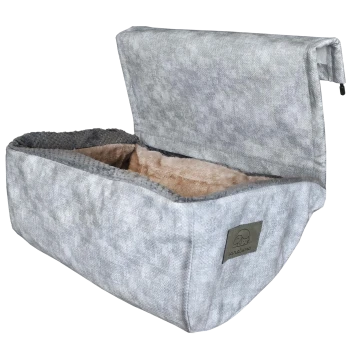 Graues Hundebett mit einem weichen, plüschigen Innenraum und einem faltbaren Deckel, mit einem kleinen Logo-Patch eines Hundes.