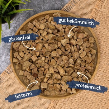 Holzschale mit kleinen braunen Snackwürfeln und deutschen Angaben: 'glutenfrei', 'fettarm', 'gut bekömmlich', 'proteinreich'.