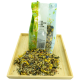 Eine Tüte "Gold Hamster Basis Futter" steht auf einem Holztablett, mit einer bunten Mischung aus Samen und getrockneten Blumen, die davor ausgekippt sind.