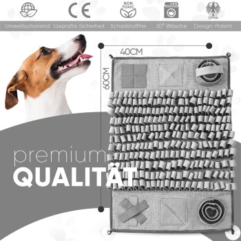 Ein glücklicher Hund mit kurzem Fell schaut neben einer grauen interaktiven Tiermatte mit verschiedenen Texturen und Formen auf, beschriftet mit 'premium QUALITÄT.'