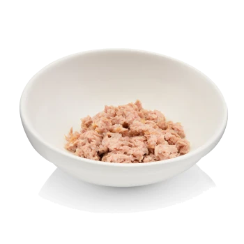 Eine weiße Schüssel gefüllt mit zerriebenem rosa Katzenfutter, das Thunfisch ähnelt, vor einem schlichten Hintergrund.