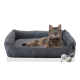 Ein gemütliches graues Katzenbett mit einer entspannten getigerten Katze darin, begleitet von zwei strukturierten Spielbällen an der Seite.