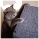 Eine graue Britisch Kurzhaar Katze mit orangefarbenen Augen, die neugierig an einem grauen Filz-Kratzbaum kratzt.