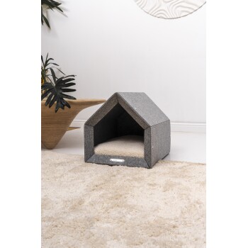 Ein gemütliches graues Haustierhaus mit einem dreieckigen Dach und einem weichen cremefarbenen Innenkissen, das auf einem plüschigen beigen Teppich steht.