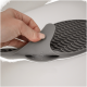 Eine Hand hält eine flexible graue Silikon-Haustierpflegeunterlage mit strukturierten Rillen, teilweise angehoben, um die Unterseite zu zeigen.