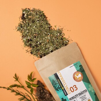 Eine Tüte mit pflanzlichem Haustierzusatz mit der Aufschrift "Mobility Kräuter" mit herausfallenden losen Kräutern, vor einem orangefarbenen Hintergrund.