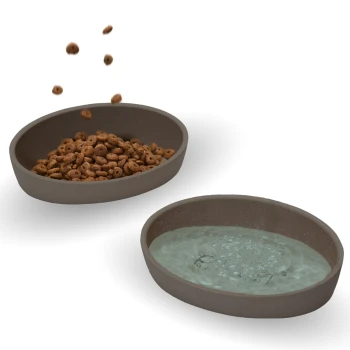 Zwei ovale Futterschalen auf einem weißen Hintergrund: eine gefüllt mit Trockenfutter und die andere mit Wasser, die Blasen zeigt.