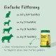 Eine klare Glasschüssel, gefüllt mit dunklem, braunem Nahrungsergänzungsmittel für Haustiere, umgeben von einem kleinen Haufen des Pulvers auf einer weißen Oberfläche.