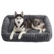 Sibirischer Husky mit blauen Augen liegt auf einem weichen, grauen, gerippten rechteckigen Hundebett mit erhöhtem Rand vor weißem Hintergrund.