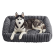 Sibirischer Husky mit blauen Augen liegt auf einem weichen, grauen, gerippten rechteckigen Hundebett mit erhöhtem Rand vor weißem Hintergrund.