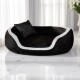 Schwarz-weißes Plüsch-Haustierbett mit passendem Kissen, auf glänzendem Marmorboden nahe weißen Vorhängen und einer Blumenvase.