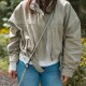 Person in beige Jacke und Jeans trägt eine beige freihändige Hundeleine quer über der Brust mit schwarzem Clip.