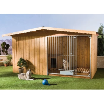 Eine hölzerne Hundehütte mit einer metallenen Gittertür, mit einem Hund darin und einem anderen Hund, der draußen auf grünem Gras liegt, mit einem blauen Ball in der Nähe.