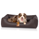 Ein glücklicher Australian Shepherd Hund, der in einem plüschigen, dunkelbraunen Haustierbett mit lederähnlicher Textur entspannt, mit einem kleinen Etikett, das "KNUFFELWUFF" liest.