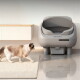 Langhaarige creme-braune Katze nähert sich einer grauen ASTROPET-Autokatzentoilette mit Bedienfeld in einem modernen Raum.