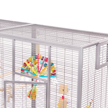 Ein geräumiger grauer Vogelkäfig aus Metall mit bunten Spielzeugen, darunter ein fächerförmiges Kauspielzeug und eine hängende Glocke, mit offener Tür.